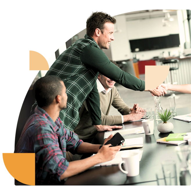 Een teamlid schudt handen met een nieuwe medewerker tijdens een meeting, waarbij het onboarding-proces van security awareness wordt besproken.