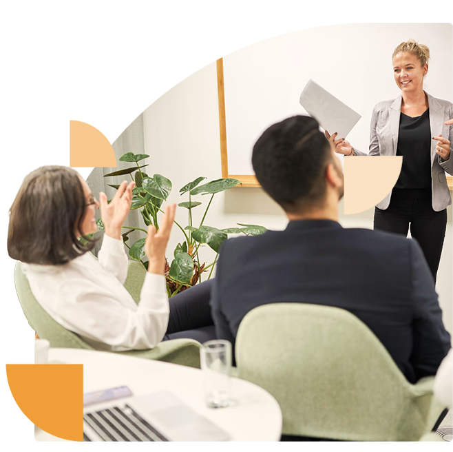 Een vrouwelijke presentator leidt een security workshop terwijl deelnemers actief betrokken zijn en vragen stellen.
