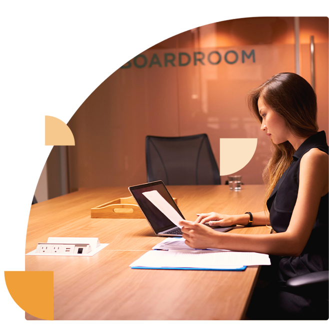 Directielid in de boardroom van een bedrijf werkt aan de interne informatiebeveiligingsstrategie op haar laptop.