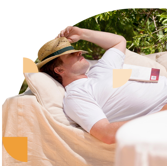 Foto van een man met hoed die geniet van zijn vakantie en buiten op een bank een boek leest.