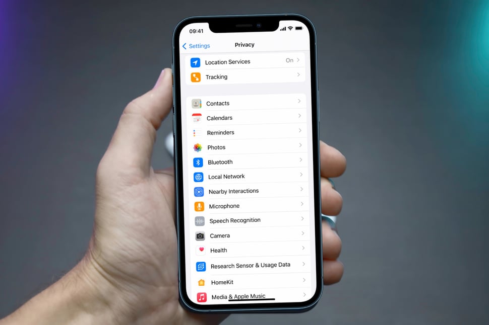 Hand houdt een iOS-smartphone vast met daarop het scherm dat de privacy-instellingen toont.