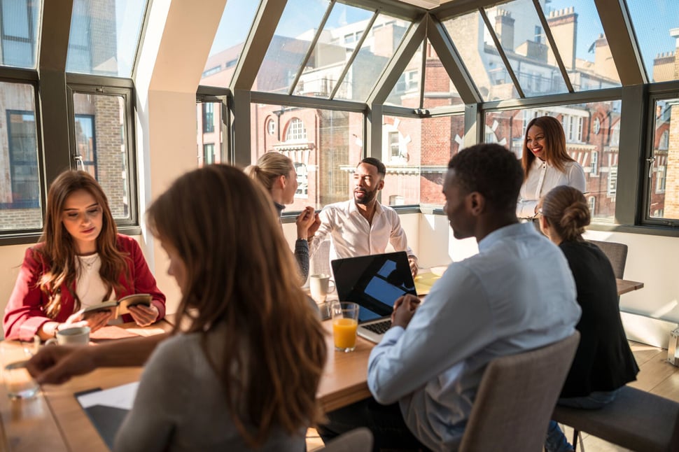 Een groep professionals neemt deel aan een security workshop, waarbij ze samenwerken en ideeën uitwisselen in een lichte, moderne vergaderruimte.