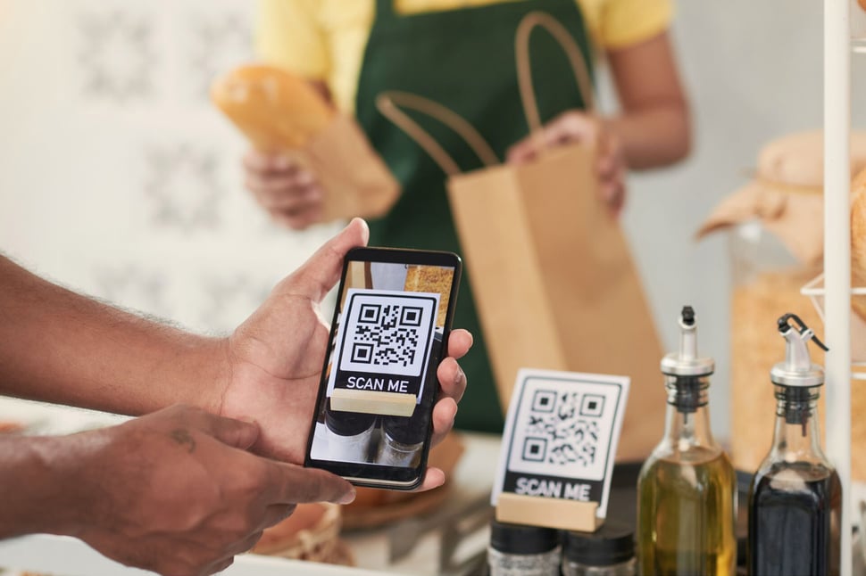 Een persoon scant een QR-code in een winkel, waarbij quishing-aanvallen een potentieel gevaar vormen.