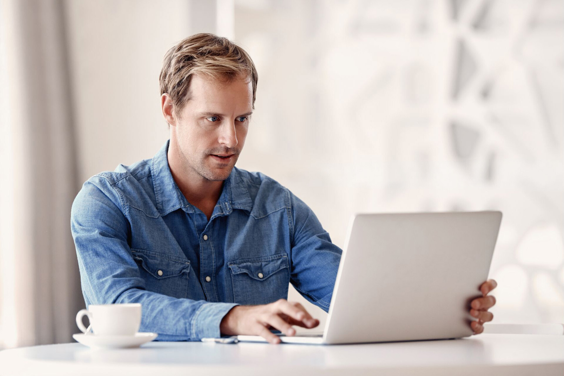 Een man bekijkt een phishing e-mail op zijn laptop, waarbij hij een urgent verzoek krijgt om geld over te maken. 