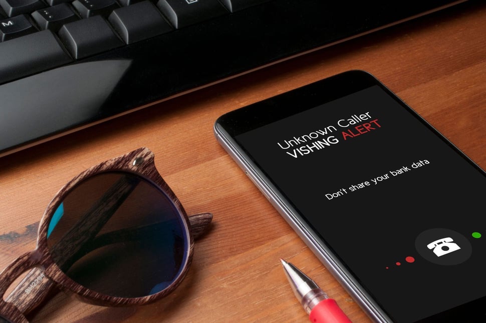 Een smartphone toont een waarschuwing voor een onbekende beller waarbij opnemen zou kunnen leiden tot vishing. 