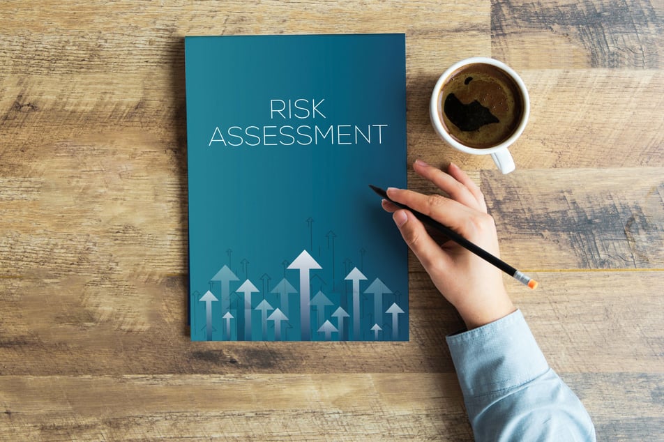 Hand met potlood naast een rapport met de titel 'Risk Assessment', essentieel in het opstellen van een incident response plan.