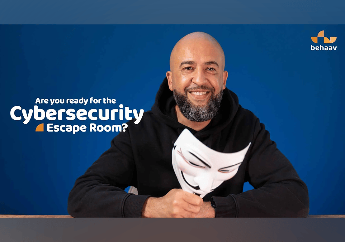 Thumbnail of a man sitting behind a desk holding an Anonymous mask with the text: Are you ready for the Cybersecurity Escape Room?
