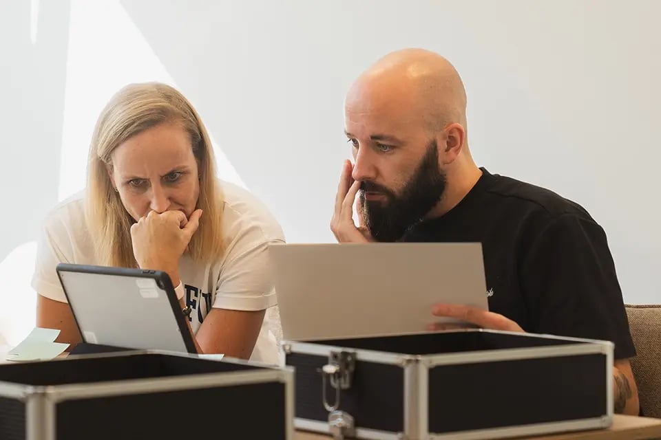 Two people team up sitting at a table and trying to solve an escape room puzzle.