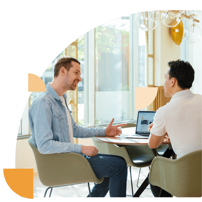 Two employees discuss ideas for cybersecurity month in an informal office setting.